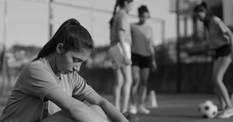 Young soccer athlete resting while teammates train